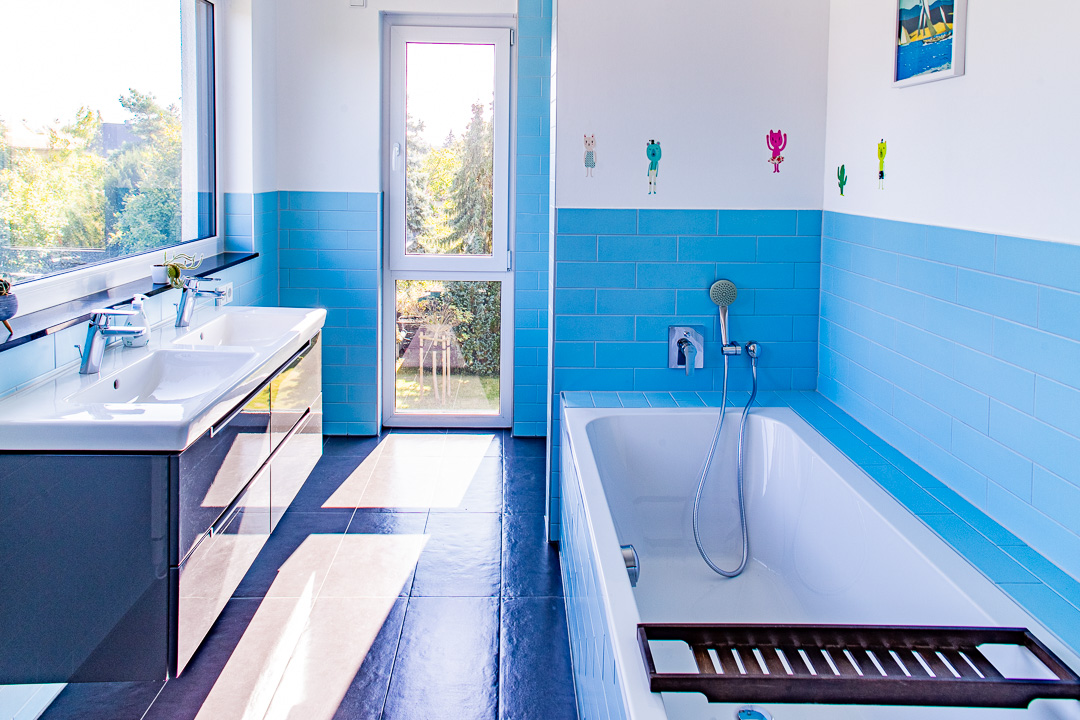 Helles, modernes Badezimmer mit blau-weißen Fliesen, zwei Waschbecken und Tageslicht. Fotografiert von Sebastian Leyser.