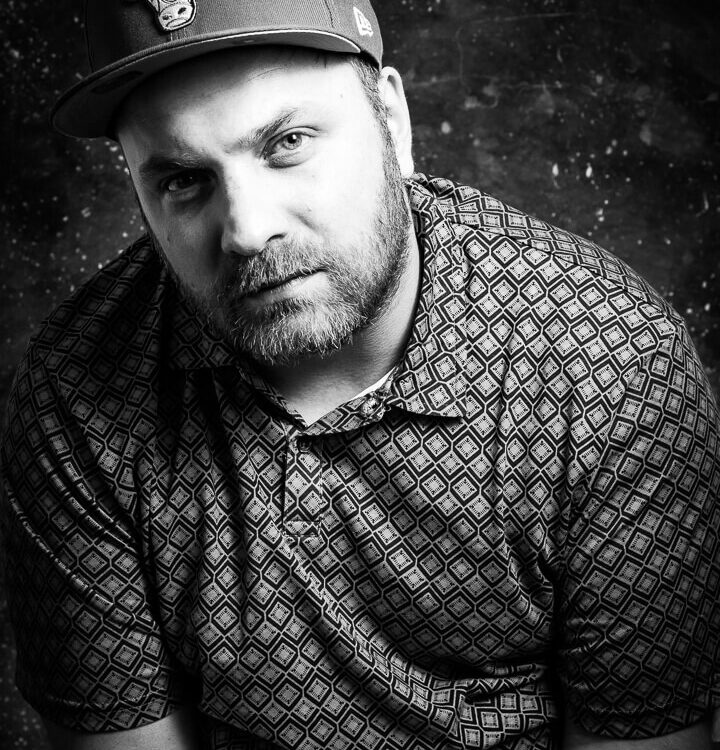 portrait eines ernst blickenden Mannes mit einem basecap, schwarz weiße Studioaufnahmen