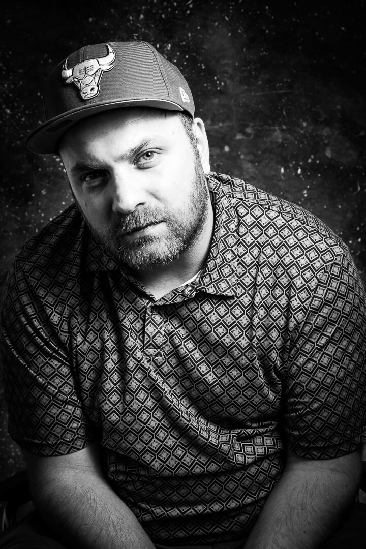 portrait eines ernst blickenden Mannes mit einem basecap, schwarz weiße Studioaufnahmen